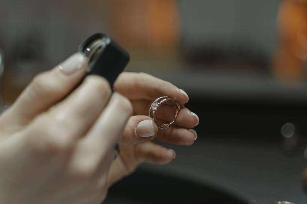 Close-up of a jeweler's hands holding a diamond ring and magnifying glass.
